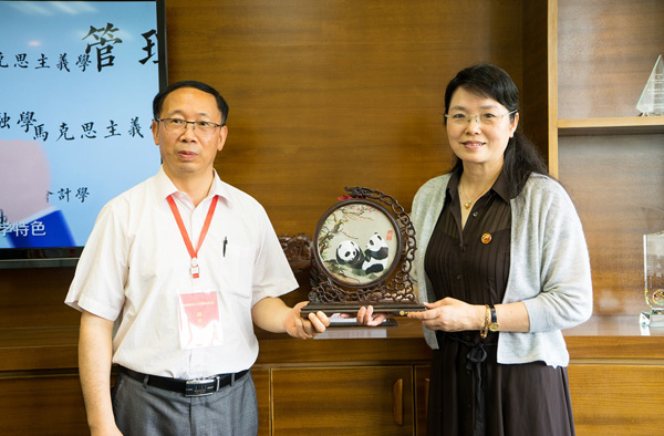 图为梁校长与西南财经大学工商管理学院分党委书记冯立互赠礼物.jpg